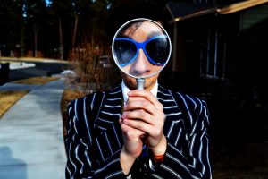 a man looking through a magnifying glass to represent how to get business on LinkedIn