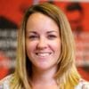 A smiling woman with straight, shoulder-length blonde hair stands in front of a blurred red and black background. Sarah Fenton, owner of SMART Bookkeeping and Accounts, growing accounting business
